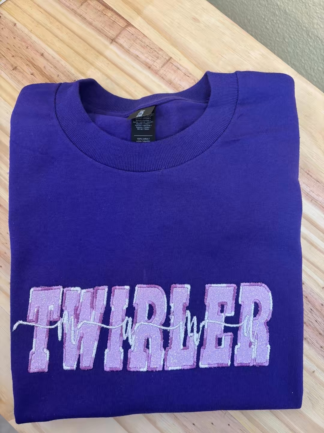 Purple crewneck sweatshirt with lilac TWIRLER embroidery, fresh from the studio